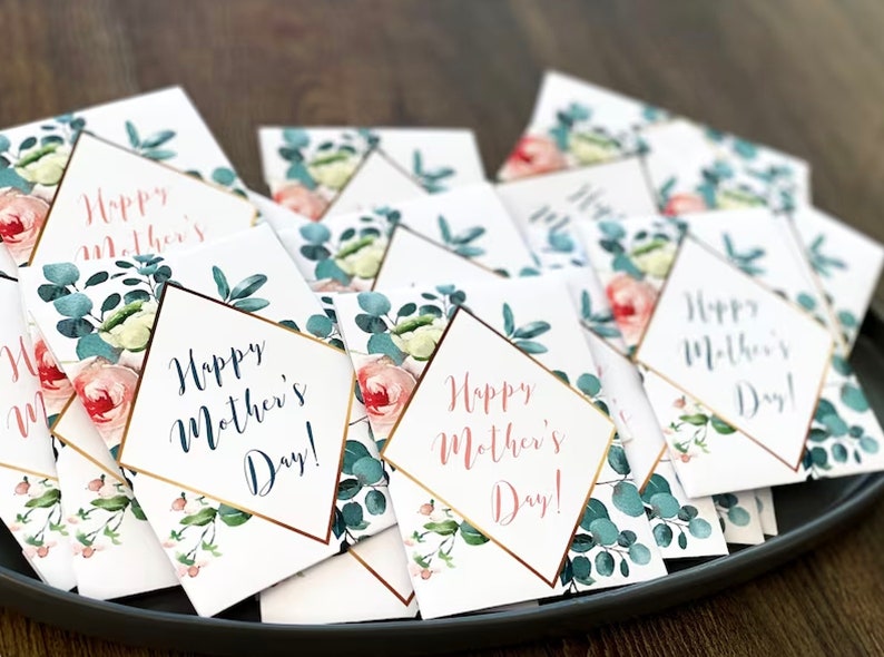 May include: A collection of Mother's Day cards with floral and botanical designs. Each card features the text "Happy Mother's Day!" in elegant script, framed by a gold border. The cards are adorned with watercolor roses and eucalyptus leaves.