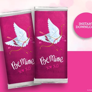 May include: Two printable Valentine's Day chocolate bar wrappers with a pink background. The wrappers feature a white dove with gold arrows and the text "Be Mine XO".