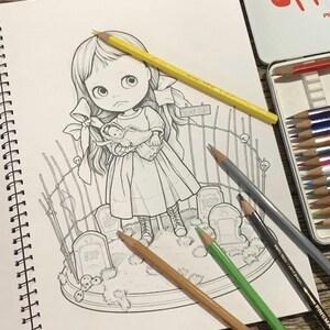 May include: A black and white line art illustration in a spiral-bound sketchbook featuring a large-eyed girl holding a small doll, standing in a graveyard with tombstones marked RIP and a fence. Several colored pencils are placed on the page.