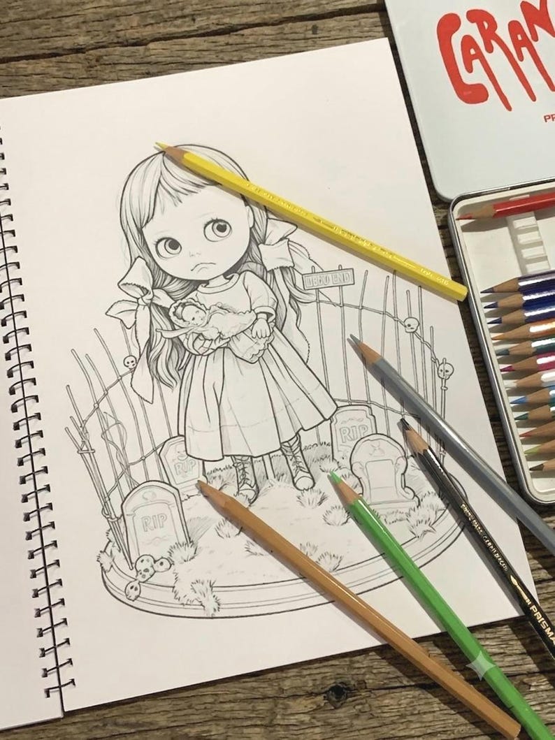 May include: A black and white line art illustration in a spiral-bound sketchbook featuring a large-eyed girl holding a small doll, standing in a graveyard with tombstones marked RIP and a fence. Several colored pencils are placed on the page.