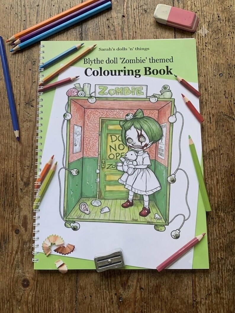 Peut inclure: Un livre de coloriage &agrave; spirales intitul&eacute; Sarah's dolls 'n' things Blythe doll 'Zombie' themed Colouring Book. La couverture pr&eacute;sente une illustration au trait d'une poup&eacute;e aux cheveux verts tenant un ours en peluche dans une pi&egrave;ce avec une porte marqu&eacute;e DO NOT OPEN.