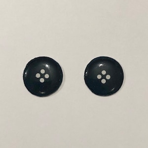 以下が含まれることがあります： 中央に白い5つの点の模様がついた黒い丸いボタンが2つ
