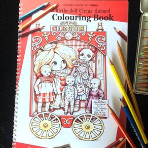 May include: A spiral-bound colouring book titled Sarah's dolls 'n' things Blythe doll 'Circus' themed Colouring Book. The cover features a red circus wagon illustration with five dolls and text reading WARNING CHILDREN LEFT UNATTENDED WILL BE SOLD TO THE CIRCUS.