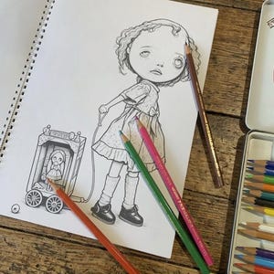Peut inclure: Un dessin au trait noir et blanc dans un carnet &agrave; spirales repr&eacute;sentant un enfant aux cheveux boucl&eacute;s tirant un petit chariot &agrave; roulettes contenant une poup&eacute;e. Plusieurs crayons de couleur, orange, vert, rose et marron, sont pos&eacute;s sur la page.