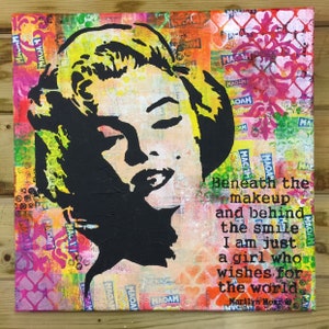 May include: A colourful abstract painting featuring a black silhouette of Marilyn Monroe's face. The background is a collage of colourful paper scraps and the quote "Beneath the makeup and behind the smile I am just a girl who wishes for the world." by Marilyn Monroe is written in black text.