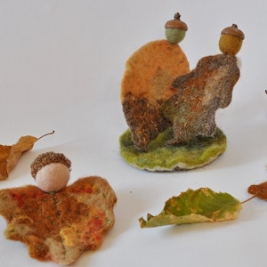 Puede incluir: Cinco adornos de fieltro con temática otoñal, que incluyen una hoja marrón y verde, una bellota marrón y verde, un pájaro marrón y verde y dos bellotas marrones y verdes con una base de fieltro marrón y verde.