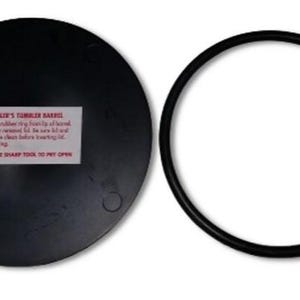 May include: A black rubber lid and a black rubber ring for a tumbler barrel. The lid has a white label with the text "THUMBLER'S TUMBLER BARREL" and instructions for use. The label also says "DO NOT USE SHARP TOOL TO PRY OPEN".