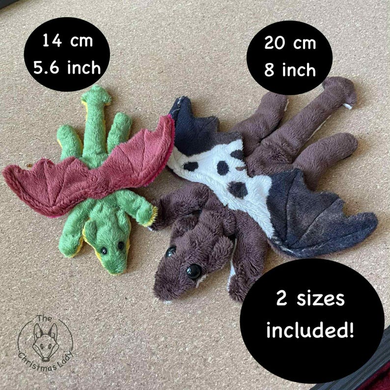 Puede incluir: Dos juguetes de peluche de drag&oacute;n en verde, burdeos y marr&oacute;n. Un drag&oacute;n mide 14 cm de largo y el otro 20 cm. La imagen incluye el texto "&iexcl;2 tama&ntilde;os incluidos!"