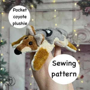 May include: A plush coyote toy with brown, gray, and tan fur. The text "Pocket coyote plushie" is in a white circle above the toy. The text "Sewing pattern" is in a white circle below the toy. The Christmas Lady logo is in the bottom left corner.