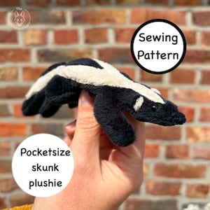 May include: A black and white plush skunk held in a hand. The skunk has a white stripe down its back. Text on the image reads "Pocketsize skunk plushie" and "Sewing Pattern". The background is a brick wall.