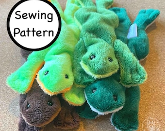 May include: A pile of plush toy lizards in shades of green and brown. The toys have small black eyes and are made of soft, fuzzy material. A white circle with the words "Sewing Pattern" is in the upper left corner.