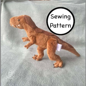 May include: A plush, brown Tyrannosaurus Rex dinosaur toy with a tag. The toy has a detailed design, including claws, teeth, and textured fur. A black circle with the words "Sewing Pattern" is in the background.