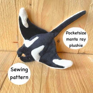 May include: A plush manta ray toy in black and white, with the text "Pocketsize manta ray plushie" and "Sewing pattern" on white circles. The toy is made of soft fabric and is designed to resemble a manta ray.