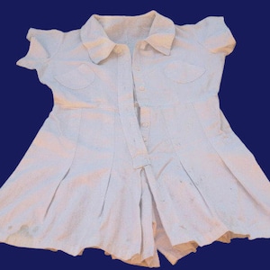 May include: A white, short-sleeved dress with a button-up front and a collar. The dress has a pleated skirt and two pockets on the chest.