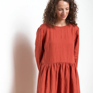 May include: A rust-colored linen dress with long sleeves and a gathered skirt.