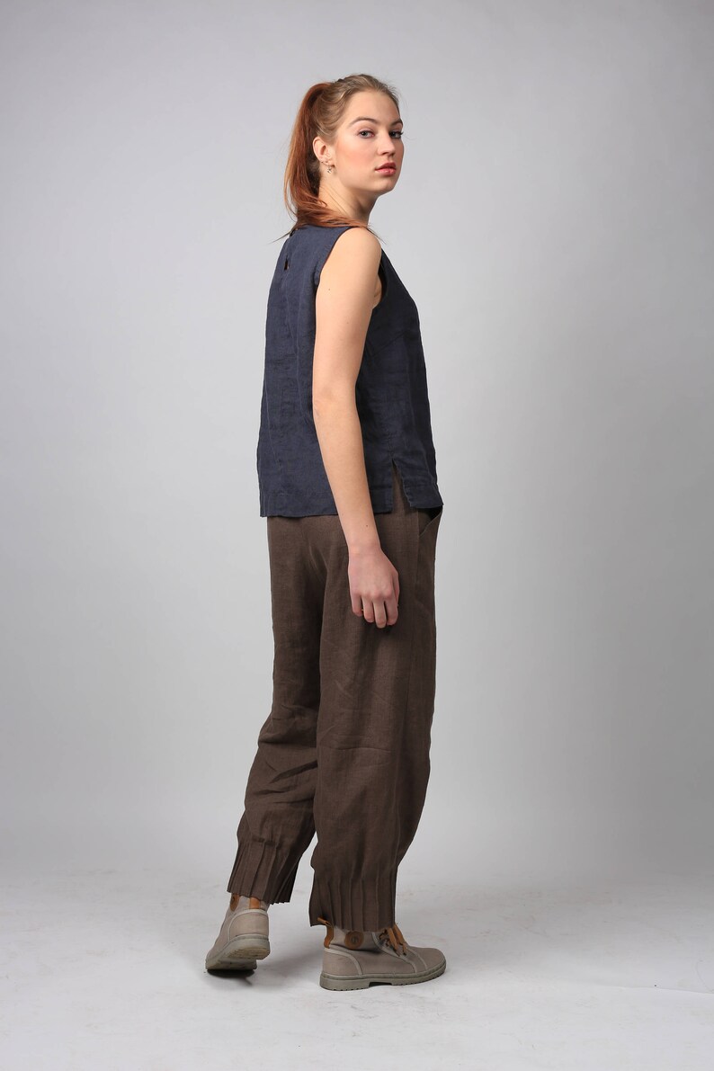 Puede incluir: Una mujer con un top azul oscuro sin mangas y pantalones de lino marr&oacute;n con dobladillos. Lleva botas de tobillo de color marr&oacute;n claro.