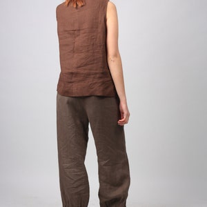 May include: A brown linen sleeveless top and matching brown linen pants with a cuffed hem. The pants are loose fitting and the top has a scoop neck.