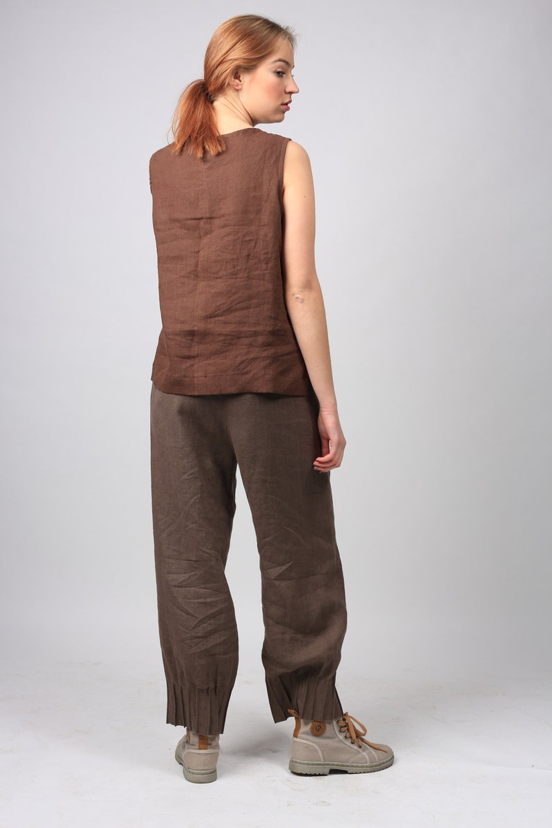 May include: A brown linen sleeveless top and matching brown linen pants with a cuffed hem. The pants are loose fitting and the top has a scoop neck.
