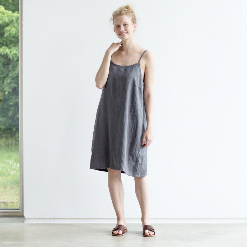 May include: A gray linen slip dress with thin straps. The dress is knee-length and has a relaxed fit.