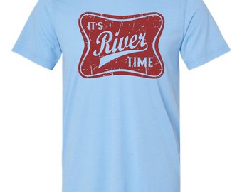 May include: A light blue short-sleeve t-shirt featuring a distressed red rectangular graphic with rounded corners. The graphic contains the white text "IT'S" above the word "River" in a script font, with the word "TIME" below it.