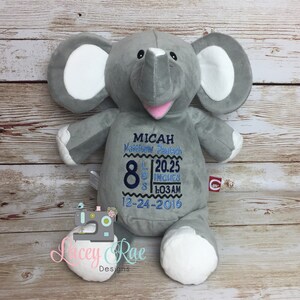 May include: Gray plush elephant stuffed animal with embroidered details. The elephant has a pink mouth and white ears. The embroidery includes the name Micah Matthew Pautsch, 8 lbs, 20.25 inches, 1:03 AM, 12-24-2016.