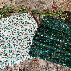 May include: Two fabric swatches featuring a Christmas holly and berry design. One swatch is white with green holly and red berries. The other swatch is dark green with green holly and red berries.