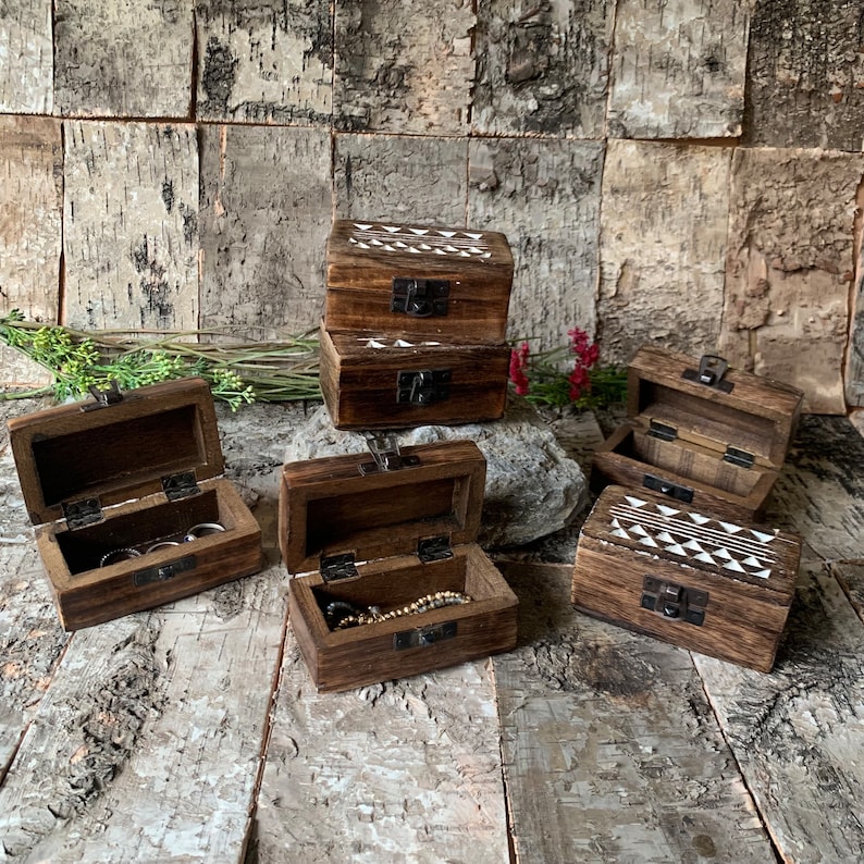 May include: Six wooden boxes with hinged lids, some with white geometric designs. The boxes are open and show the interior, which is empty or contains rings or a necklace.