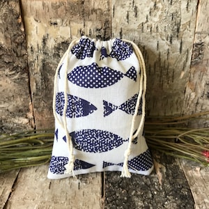 May include: A small white drawstring bag with a blue fish pattern. The fish are printed in a dark blue colour and have a white polka dot pattern.