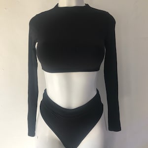 Może przedstawiać: Czarny top z długim rękawem i wysokie bikini.