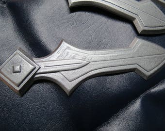 May include: Two silver-colored metal sword-shaped pieces with a textured surface. The pieces have a pointed tip and a rounded base.