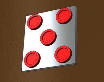 May include: A silver square with five red circles arranged in a 2-1-2 pattern. The circles are raised and have a defined edge. The background is a solid brown color.