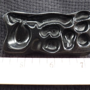 Pode incluir: Um molde de pl&aacute;stico preto com um design em relevo da palavra "Ore" em uma fonte estilizada. O molde mede aproximadamente 12,7 cm de comprimento e 5 cm de largura.