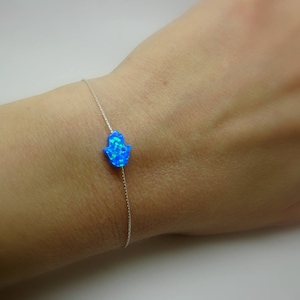 May include: A silver chain bracelet with a blue opal hamsa hand charm.