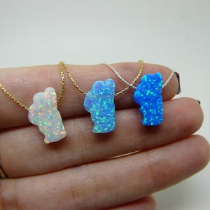 May include: Three necklaces with opal pendants in the shape of a cloud. The pendants are white, light blue, and dark blue.