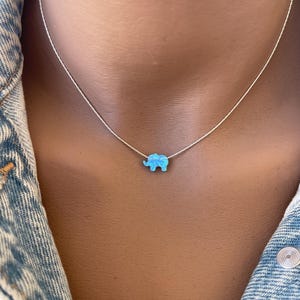 May include: A silver chain necklace with a blue opal elephant pendant.