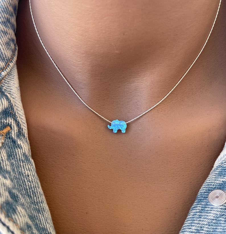 May include: A silver chain necklace with a blue opal elephant pendant.