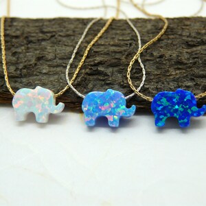 May include: Three delicate necklaces with opal elephant pendants. The elephants are in white, blue, and light blue.