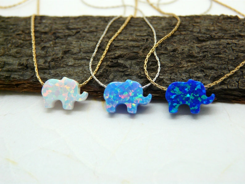 May include: Three delicate necklaces with opal elephant pendants. The elephants are in white, blue, and light blue.