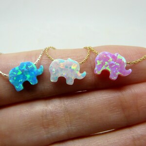 May include: Three gold necklaces with opal elephant pendants. The elephants are in shades of blue, white, and pink.