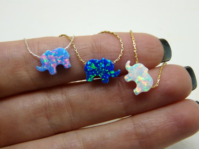 May include: Three gold chain necklaces with opal elephant pendants. The elephants are in blue, white, and green.