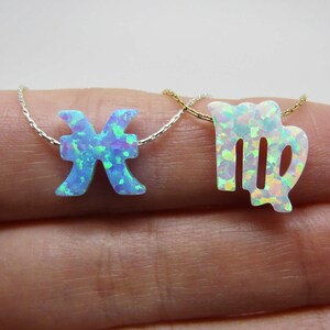 May include: Two delicate necklaces with opal zodiac signs. The first necklace features a blue opal Pisces symbol, while the second necklace features a white opal Virgo symbol.