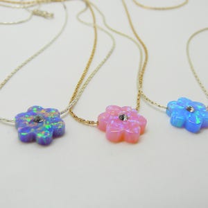 Puede incluir: Tres collares con colgantes en forma de flor. Los colgantes son de colores opalinos: morado, rosa y azul, cada uno con un peque&ntilde;o cristal en el centro. Las cadenas son delicadas, en plata y oro.