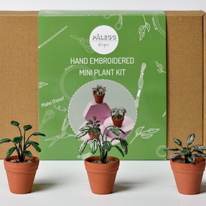 May include: A set of three hand-embroidered mini plant kits in terracotta pots. The kits are packaged in a brown box with a green label that reads "Hand Embroidered Mini Plant Kit" and "Palegg Designs".