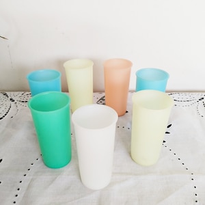 以下が含まれることがあります： 白いレースのテーブルクロスの上に、薄い青、緑、黄色、桃色など、さまざまなパステルカラーのフロストガラスのタンブラーが7つ並んでいます。