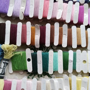 May include: A close-up of a collection of embroidery floss spools organized by color. The spools are labeled with numbers and the letter "F".