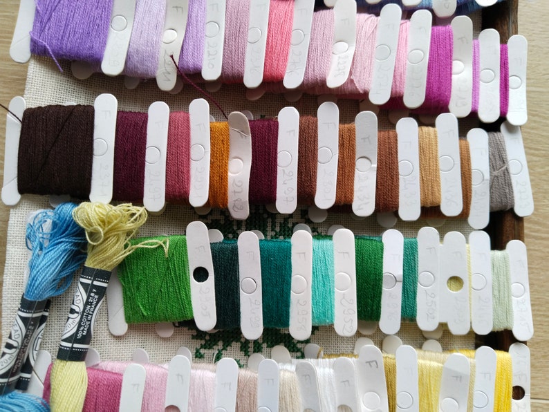 May include: A close-up of a collection of embroidery floss spools organized by color. The spools are labeled with numbers and the letter "F".