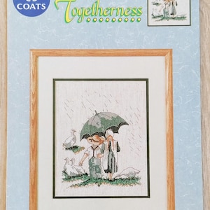 Peut inclure: Modèle de point de croix représentant un couple marchant sous un parapluie sous la pluie avec des oies. Le modèle est intitulé "Togetherness" et est de Steve Polomchak. Le modèle est de Coats.