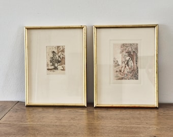 Peut inclure: Deux gravures encadrées vintage avec des cadres dorés. Les gravures présentent des illustrations détaillées en noir et blanc. L'une représente une figure portant des objets, l'autre une scène avec des personnages près d'une porte. Les cadres sont rectangulaires.