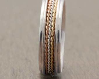 May include: A silver band with a braided design in three different shades of gold.