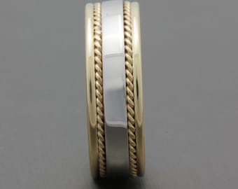 May include: A gold and silver wedding band with a rope design. The band is wide and has a polished finish.
